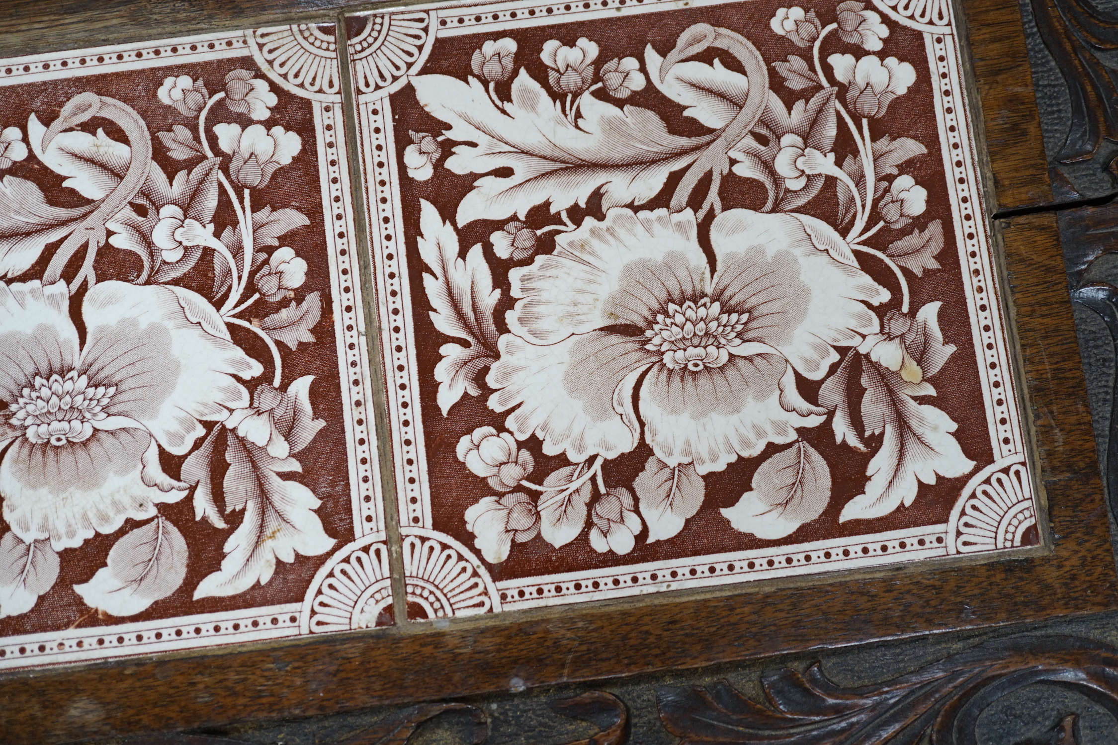 A Victorian carved oak stand inset with there floral tiles, 69cm wide